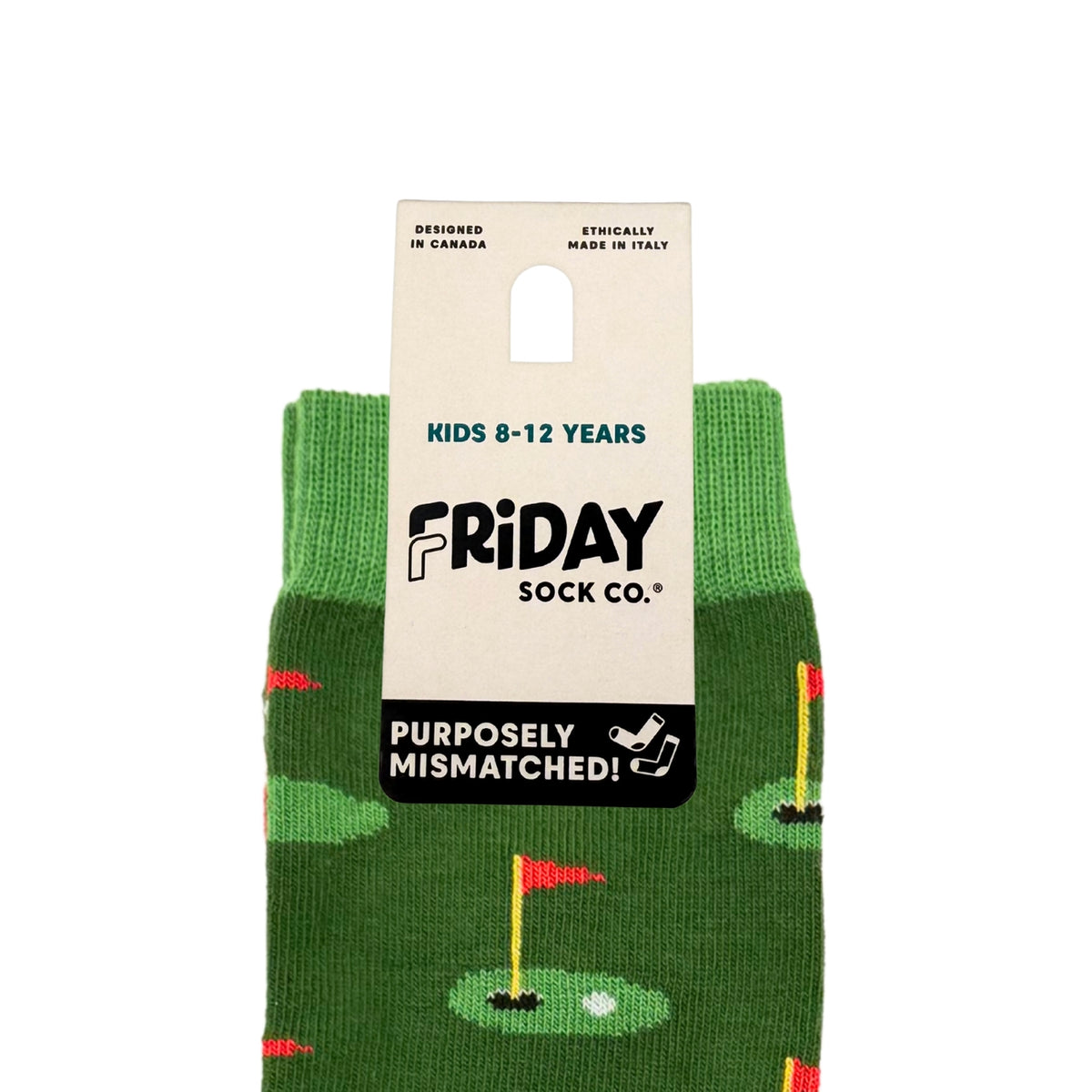 A pair of green children's socks with a golf course pattern, featuring a white cardboard hanger label that reads 'Friday Sock Co.' and 'Purposefully Mismatched!'.