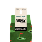 A pair of green children's socks with a golf course pattern, featuring a white cardboard hanger label that reads 'Friday Sock Co.' and 'Purposefully Mismatched!'.