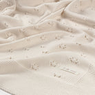 Close-up of a textured beige blanket with a brand label.