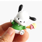 Small white dog figurine with black ears holding an ice cream cone, held in a hand against a white background.