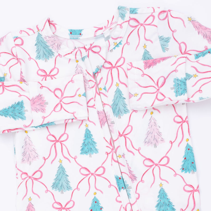 A white long-sleeve baby pajama top with a festive Christmas print featuring pink bows, teal and pink Christmas trees, and small gold stars.