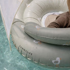 Child in a gray inflatable ring with 'Sunnylife' branding in a pool.