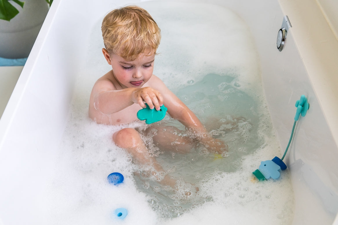Child playing with a toy in a bathtub using a suction cup attachment.