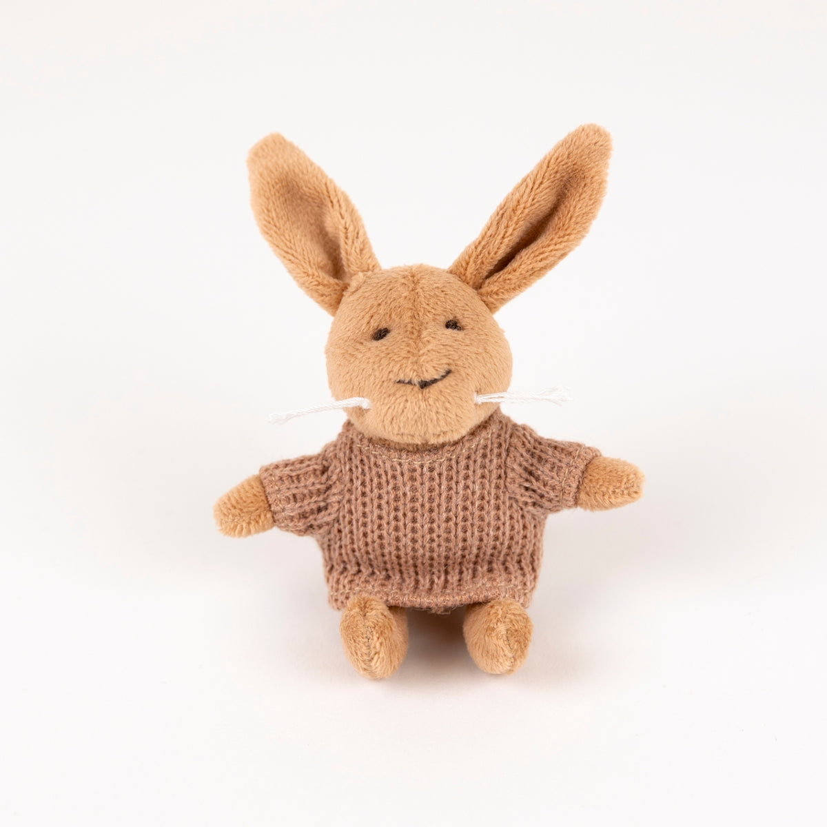 Knitted brown sweater on a beige bunny toy on a white background