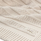 Close-up of a textured beige knitted blanket with 'it & me' branding.