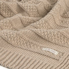 Close-up of a beige knitted blanket with a brand label.