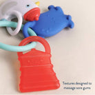 Colorful baby teething toy with text 'Textures designed to massage sore gums' on a light background