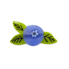 Blue glass bead with a white flower design on green leaves against a white background