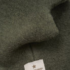 Close-up of dark green fabric with a brand label featuring a star emblem.