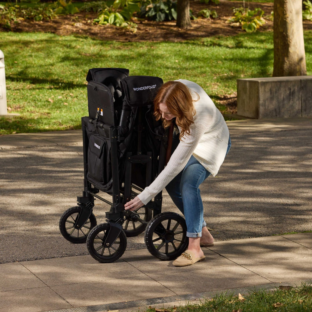Woman adjusting a stroller in a park setting