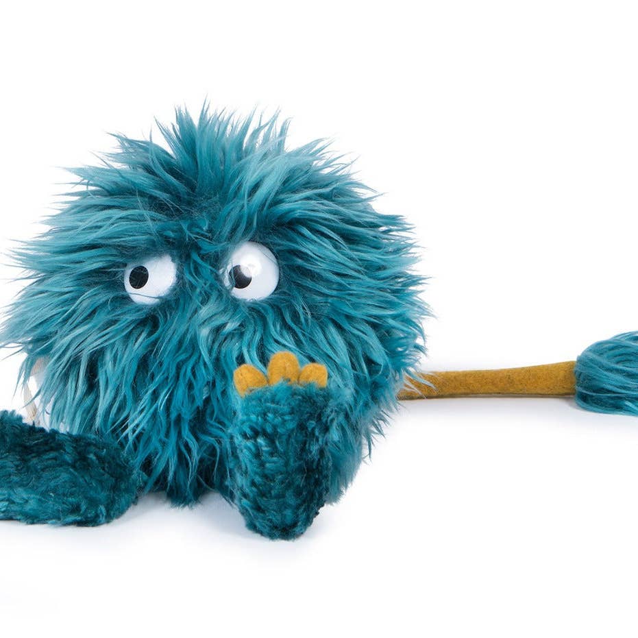 Blue plush toy with googly eyes and a yellow stick on a white background