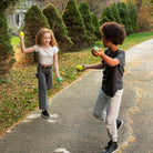 Two children playing with balls on a path in a park.