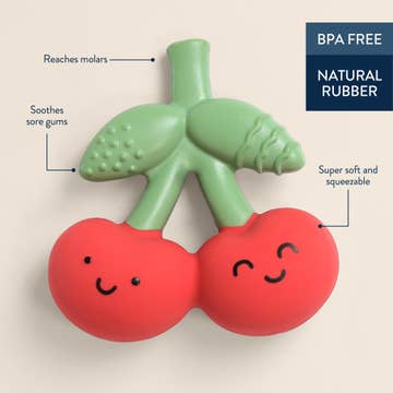 Green and red baby teether with smiling faces on a beige background, labeled for features.