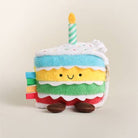 Plush toy cake with a candle on a beige background