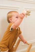 Child holding a stuffed animal in front of a white wall