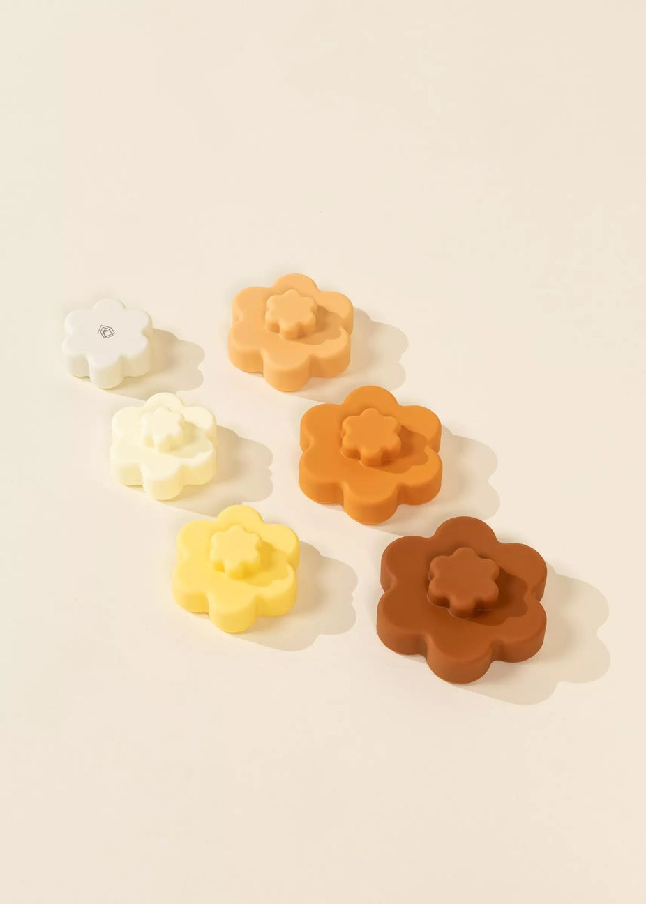 Set of flower-shaped rubber stamps in various colors on a beige background