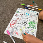 Coloring book with various designs on a surface with markers around