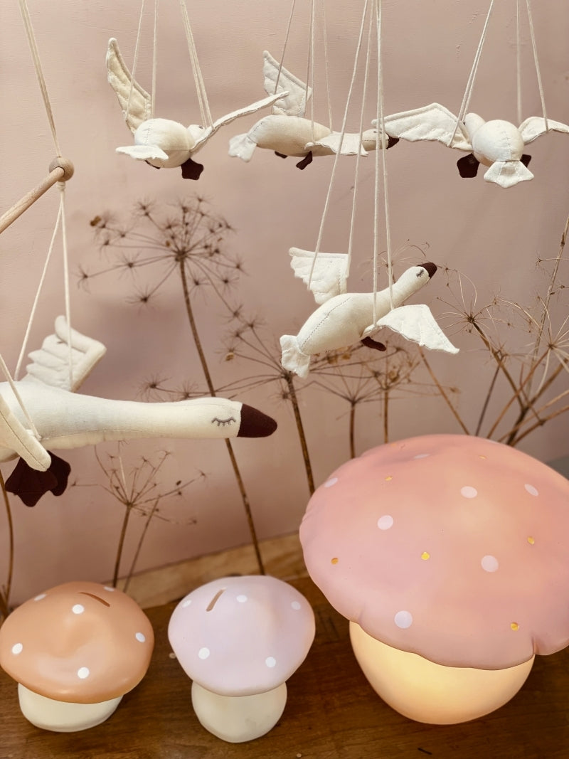Decorative hanging birds and mushroom-shaped lights on a wooden surface with a neutral background.