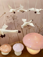 Decorative hanging birds and mushroom-shaped lights on a wooden surface with a neutral background.