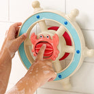 Toy steering wheel with a crab handle, being used by hands with soap bubbles on a white background.