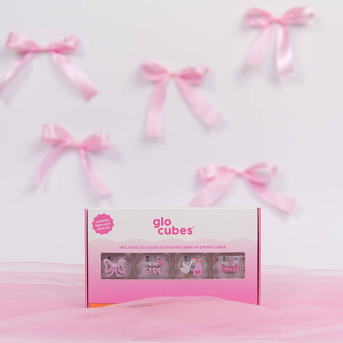 Box of glo cubes with pink ribbons on a light background