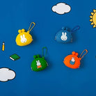 Four colorful keychains with cartoon characters on a blue background with clouds and a sun.