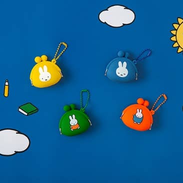Four colorful keychains with cartoon characters on a blue background with clouds and a sun.
