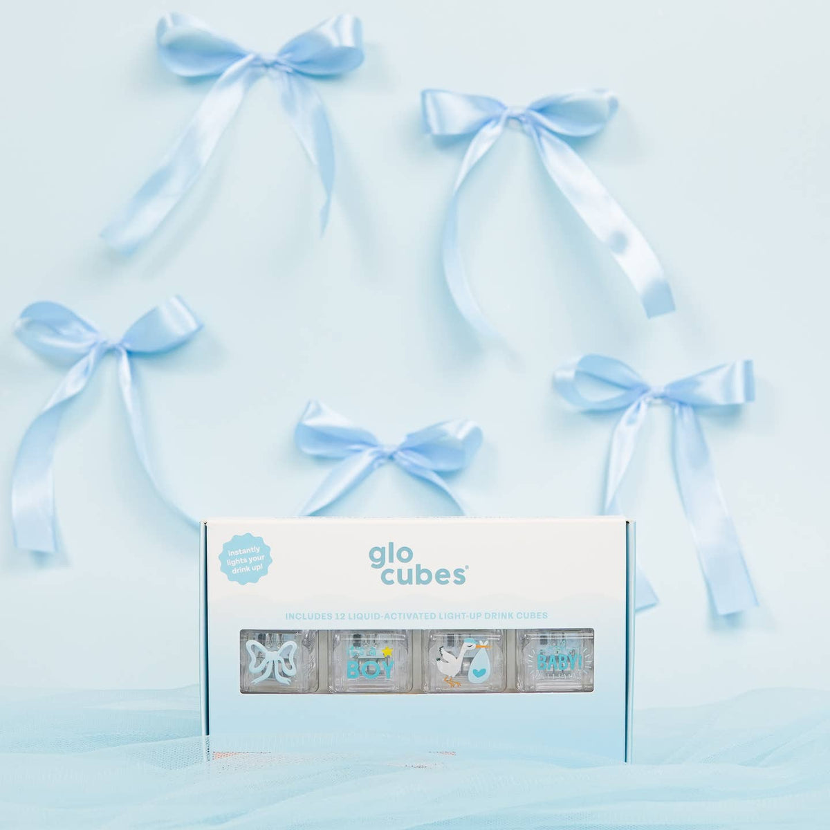 Box of glo cubes with decorative ribbons on a light blue background