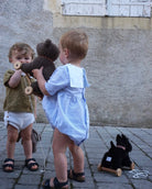 Two children playing with toys on a stone pavement.