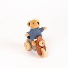 Toy bear in a sweater riding a wooden scooter on a white background