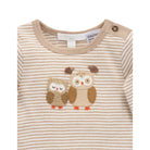 A close-up of a baby long-sleeve top with beige and white horizontal stripes, featuring two embroidered owls on the chest and a button on the shoulder.