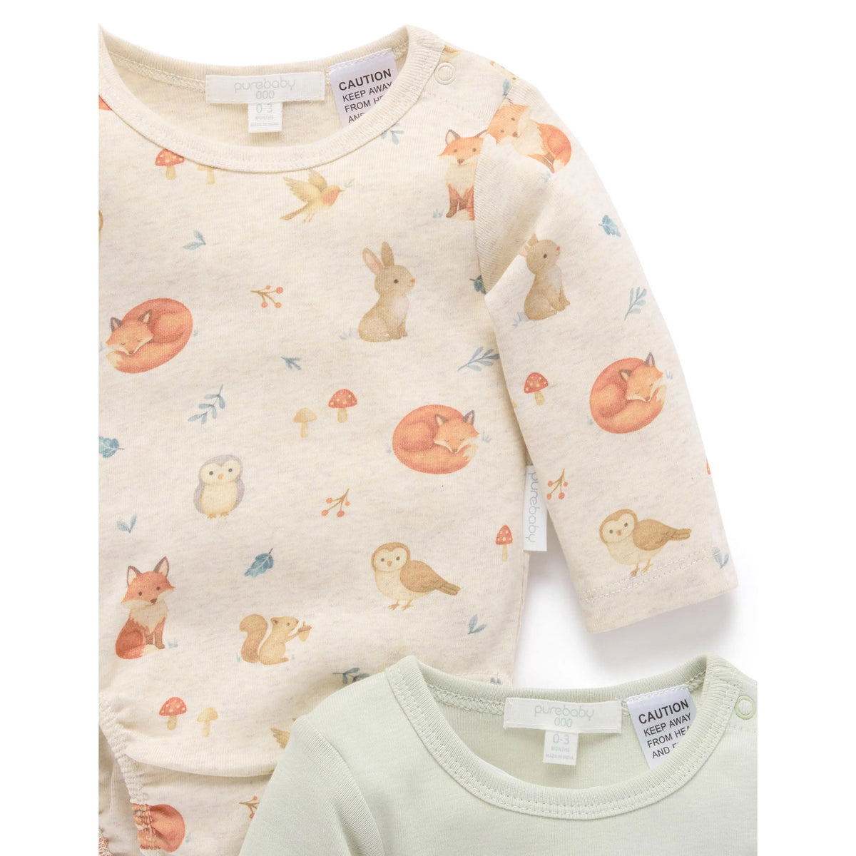 Two baby long-sleeve bodysuits from The Peony Child, one in cream with a woodland animal print (foxes, rabbits, owls, mushrooms) and one in pale sage green, shown on a white background.