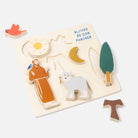 Wooden puzzle with Saint Francis, wolf, sun, moon, and leaf pieces on a light background.