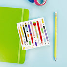 Sheet of colorful stationery items with a green notebook and pencil on a blue background