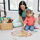 Woman and child playing with a wooden puzzle on the floor.