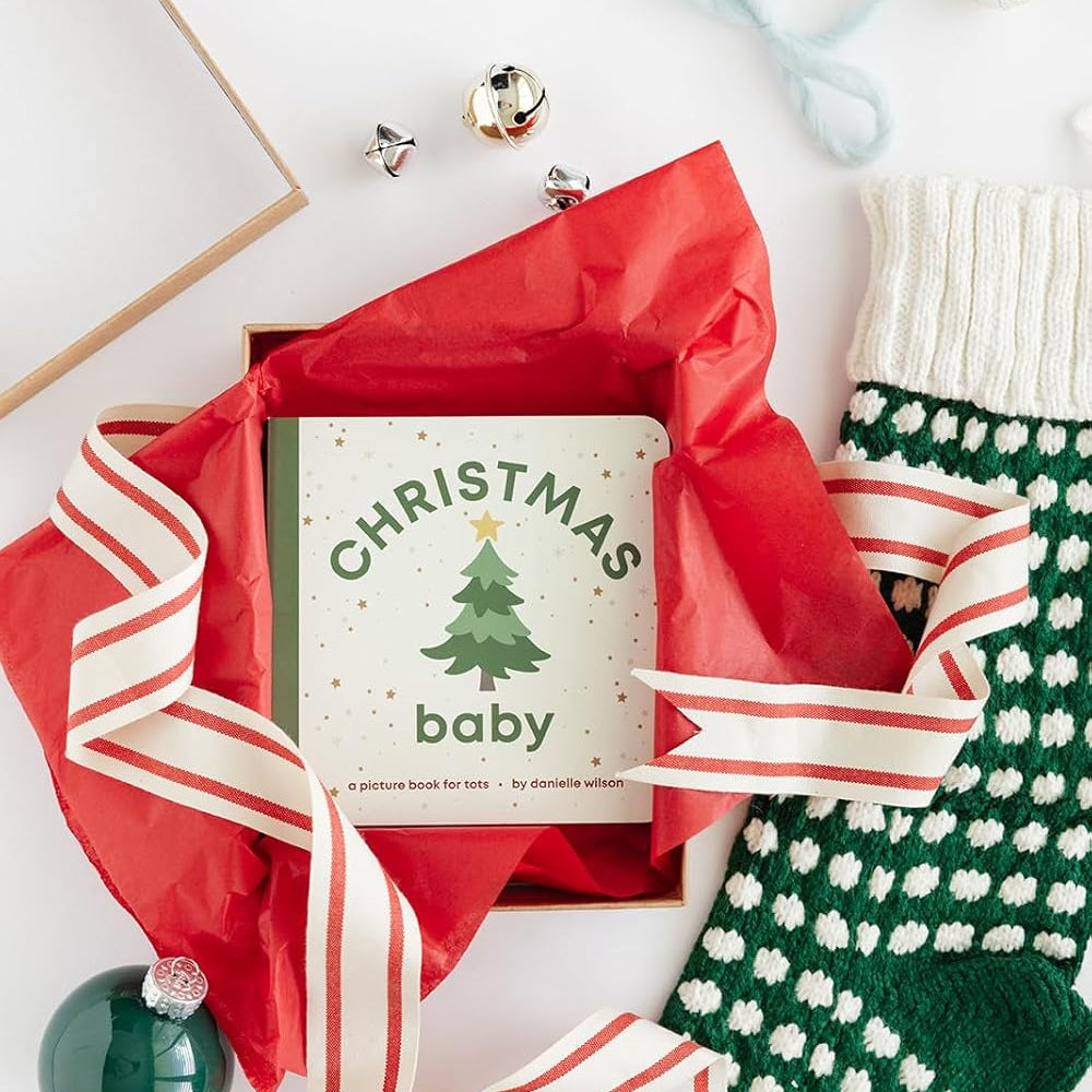 Gift box with red ribbon, Christmas-themed card, and green and white stocking on a white background