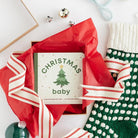 Gift box with red ribbon, Christmas-themed card, and green and white stocking on a white background