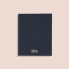 Dark blue notebook with a brand logo on a beige background