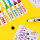 Colorful markers and a coloring book on a yellow background