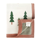 A folded knit baby blanket by Viverano, featuring a cream-colored front with green pine tree motifs and a dusty rose pink ribbed border. The underside is shown folded over, revealing a striped pattern in sage green and cream, with a white brand label sewn onto the corner.