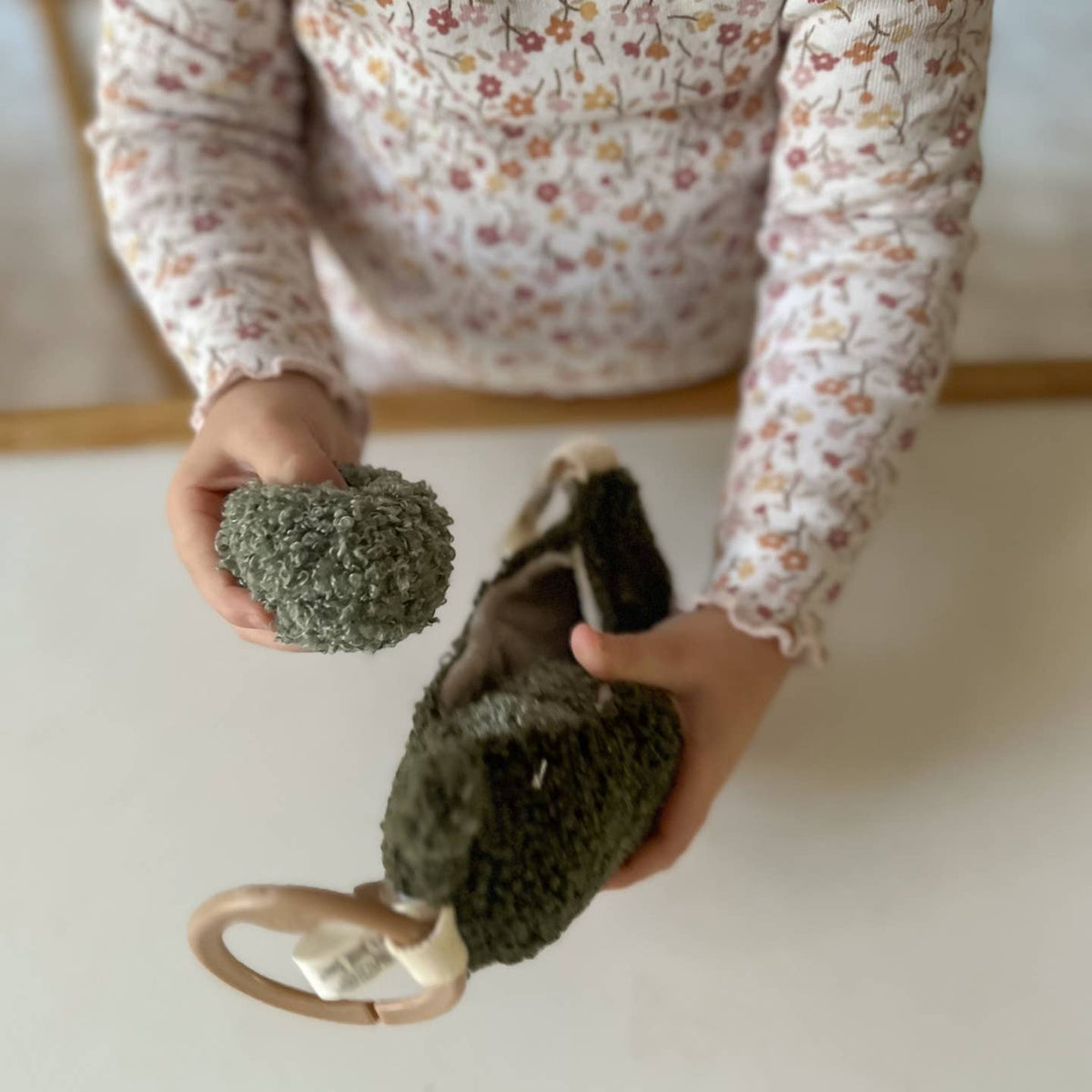 Person holding two textured green objects on a light background