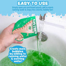 Hand pouring a green bubble bath packet into a bathtub with bubbles and text on a blue background.