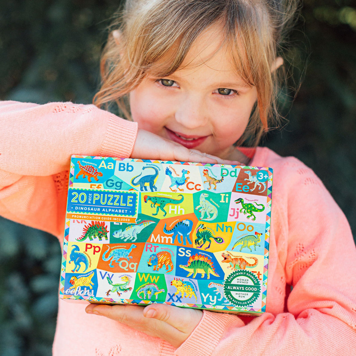 Child holding a colorful dinosaur-themed puzzle box