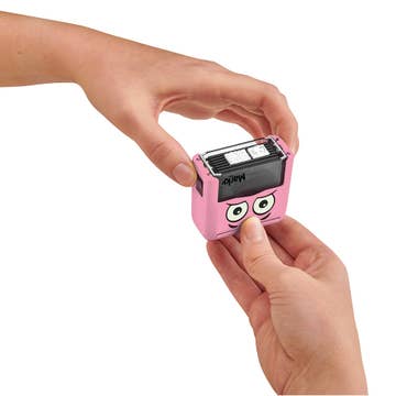 Pink character-shaped camera held by a hand on a white background