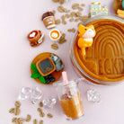 Collection of miniature food items and a jar with a bear figurine on a pink background