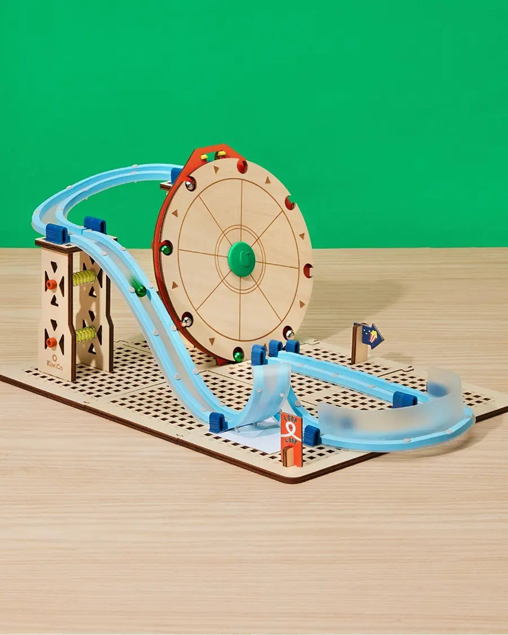 Toy track set with a wooden wheel and colorful cars on a green background