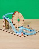 Toy track set with a wooden wheel and colorful cars on a green background