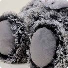 A close-up view of the Opossum by Warmies stuffed animal, highlighting its soft gray paws and fluffy black-and-gray textured fur.
