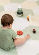 Child playing with wooden toys on a foam play mat