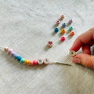 Handcrafting a colorful bead and letter bead necklace on a textured fabric background